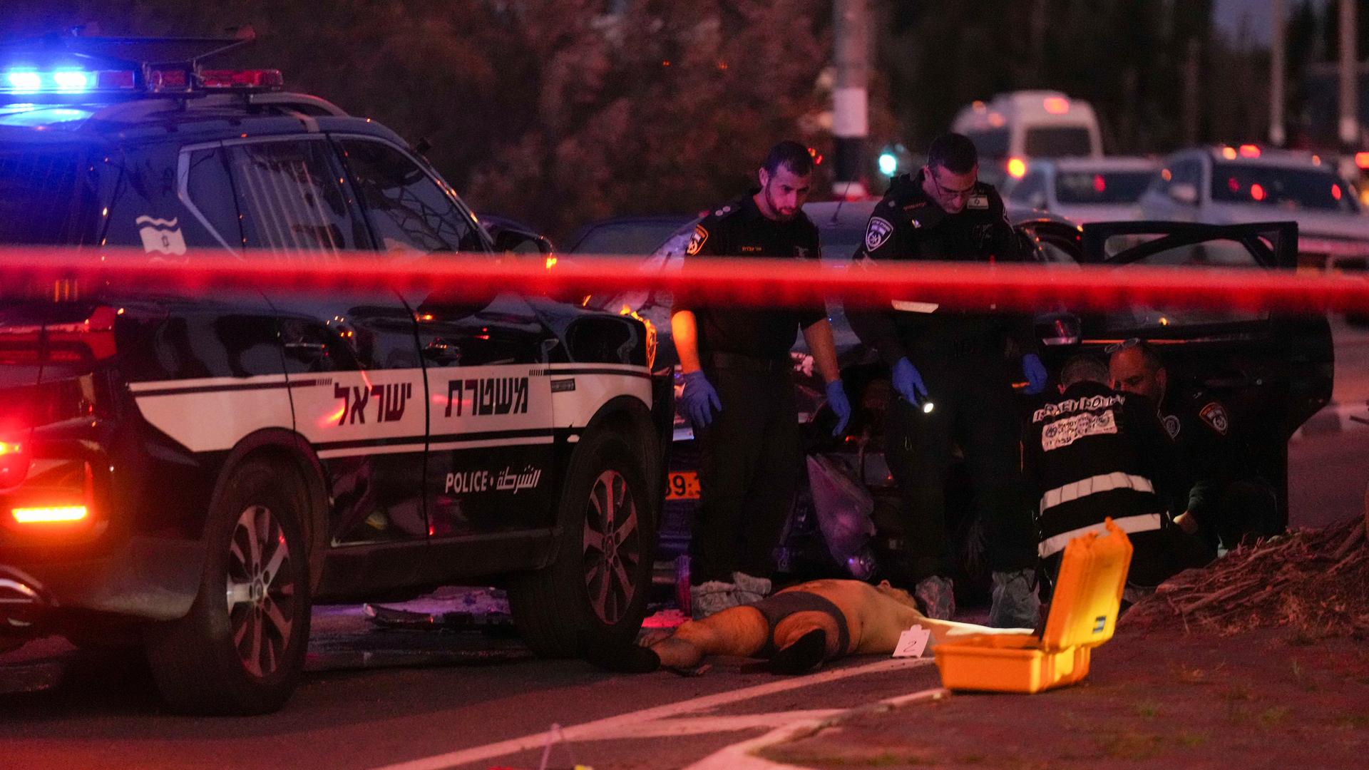 Das Foto zeigt einen Polizisten, der einen am Boden liegenden Mann untersucht. Dieser soll mit seinem Auto in eine Gruppe von Menschen gefahren sein.