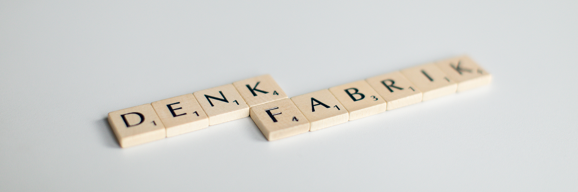Scrabblesteine mit dem Wort Denkfabrik vor weißem Hintergrund