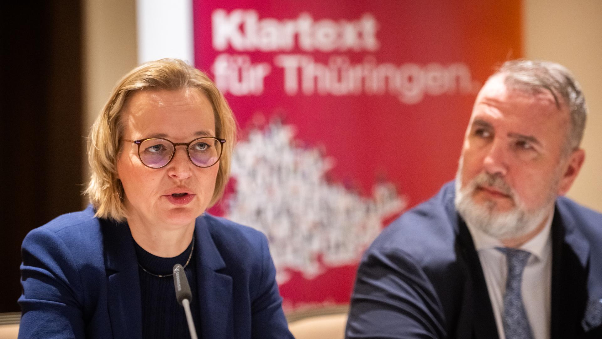 Auf dem Bild sieht man die Landesvositzenden des Bündnis Sahra Wagenknecht vor einem Mikrofon sitzen. Im Hintergrund erkennt man unscharf den Schriftzug "Klartext für Thüringen"