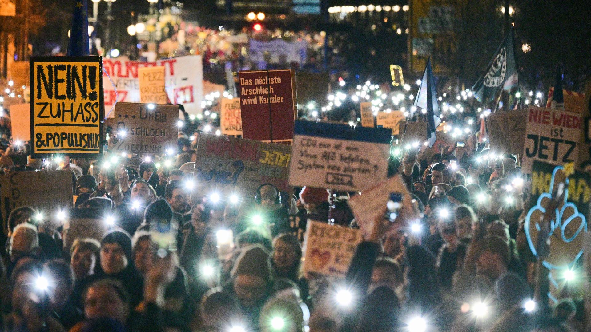 Eine Demonstration, die Menschen halten Schilder in die Höhe und haben das Licht ihrer Handys an. Es ist eine Kundgebung gegen die Zusammenarbeit der CDU mit der AfD. 