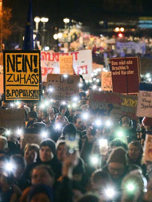 Eine Demonstration, die Menschen halten Schilder in die Höhe und haben das Licht ihrer Handys an. Es ist eine Kundgebung gegen die Zusammenarbeit der CDU mit der AfD. 