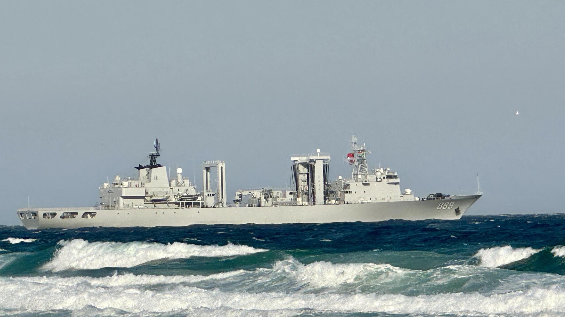 Ein Kriegsschiff kreuzt auf dem Wasser. Im Vordergrund sind starke Wellen zu sehen.