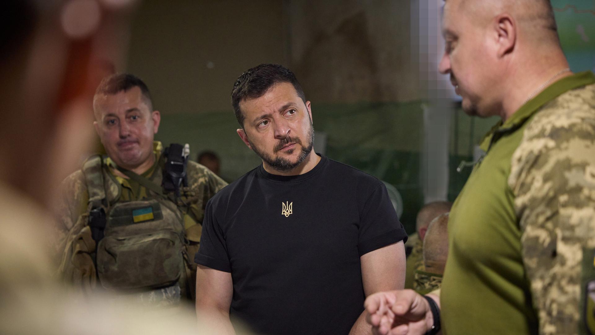 Ukraines Präsident Wolodymyr Selenskyj umringt von zwei Soldaten beim Truppenbesuch an der Front nahe von Saporischschja.