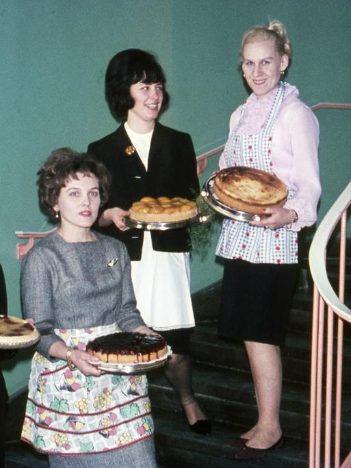 Vier Hausfrauen mit frisch gebackenem Kuchen stehen auf einer Treppe, ca. 1960.