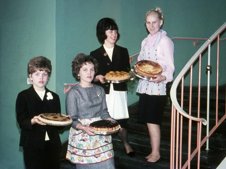 Vier Hausfrauen mit frisch gebackenem Kuchen stehen auf einer Treppe, ca. 1960.