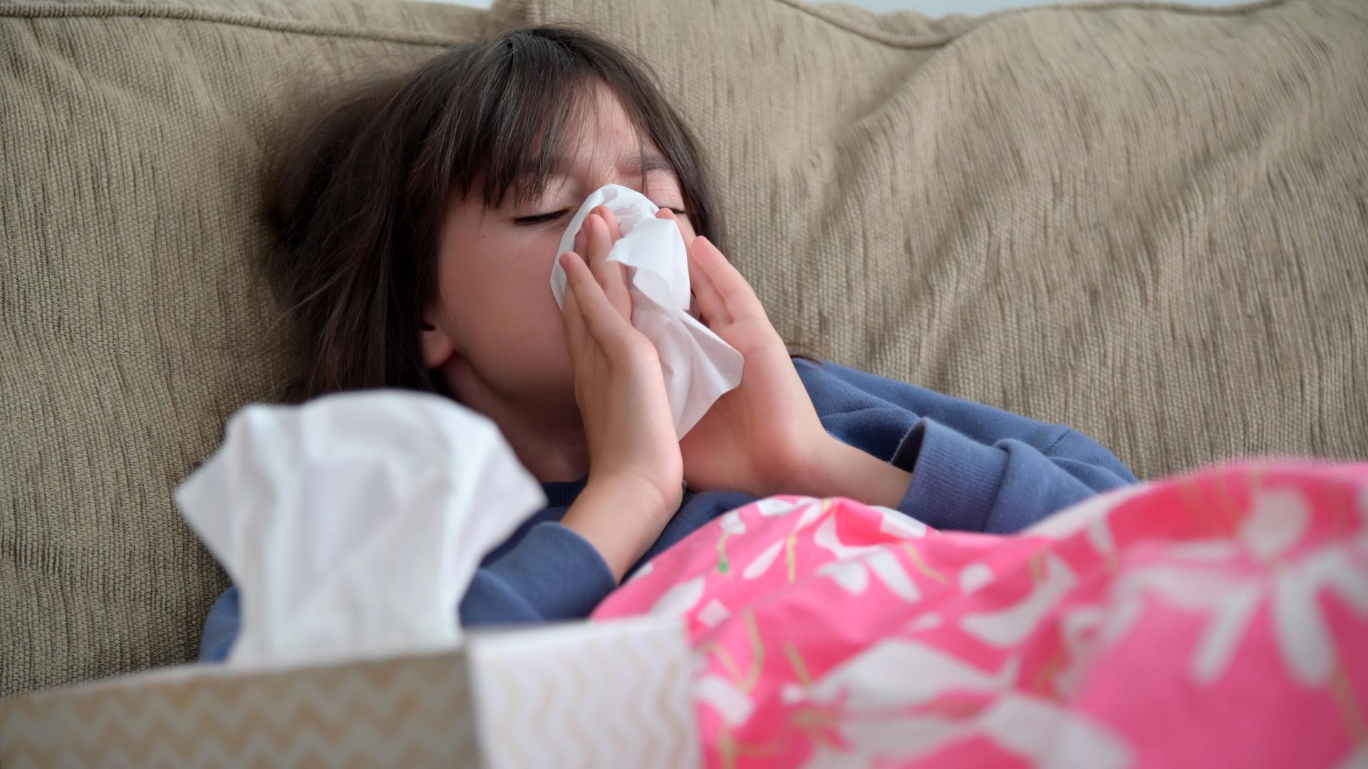 Ein Mädchen schnaubt ihre Nase in ein Taschentuch.