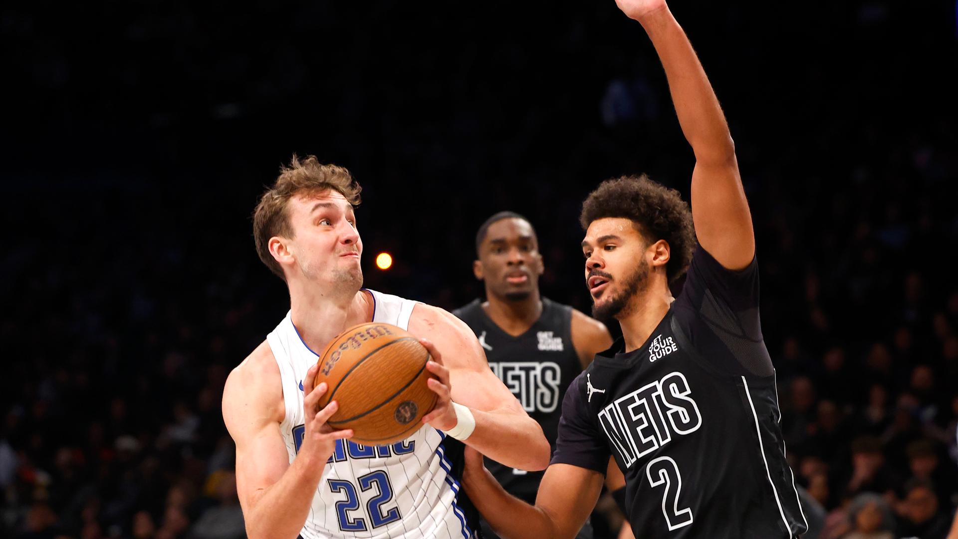 Basketball-Spieler Franz Wagner hält den Ball in beiden Händen und wird von einem Gegenspieler verteidigt. Basketball-Spieler Franz Wagner hält den Ball in beiden Händen und wird von einem Gegenspieler verteidigt.