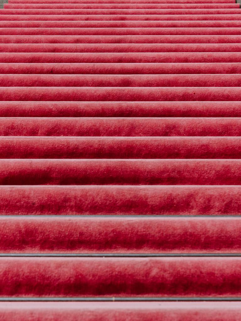 Ein leerer roter Teppich führt auf Steinstufen nach oben.