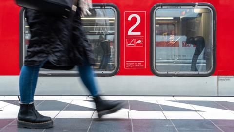 Fahrgast im Hauptbahnhof von Frankfurt Main geht am Gleis an einem Zug vorbei.