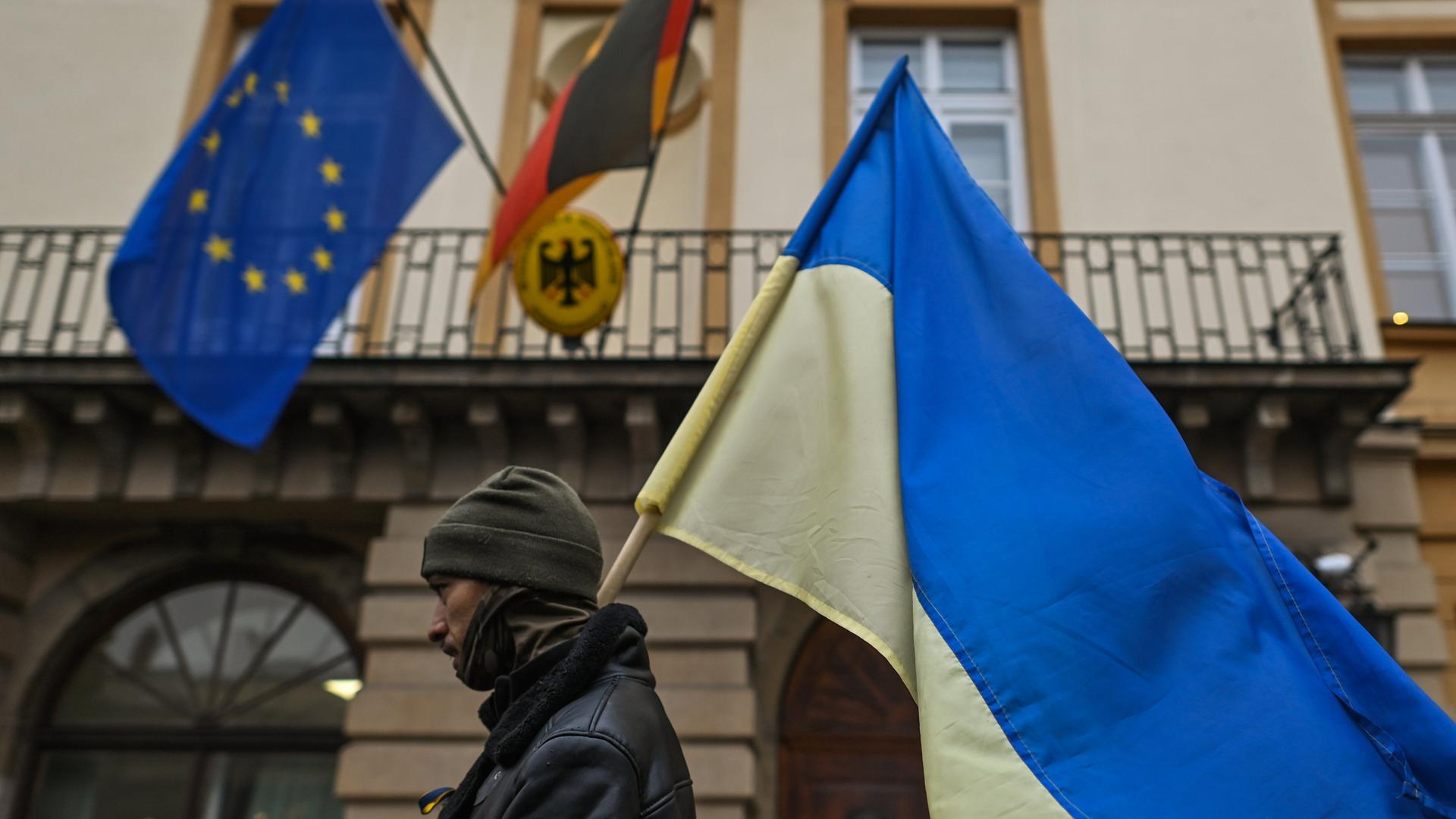 Ein Polin geht mit einer ukrainischen Flagge am Generalkonsulat der Bundesrepublik Deutschland in Krakau vorbei, während des "Protestes zur Unterstützung der Ukraine".