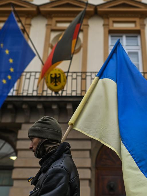 Ein Polin geht mit einer ukrainischen Flagge am Generalkonsulat der Bundesrepublik Deutschland in Krakau vorbei, während des "Protestes zur Unterstützung der Ukraine".