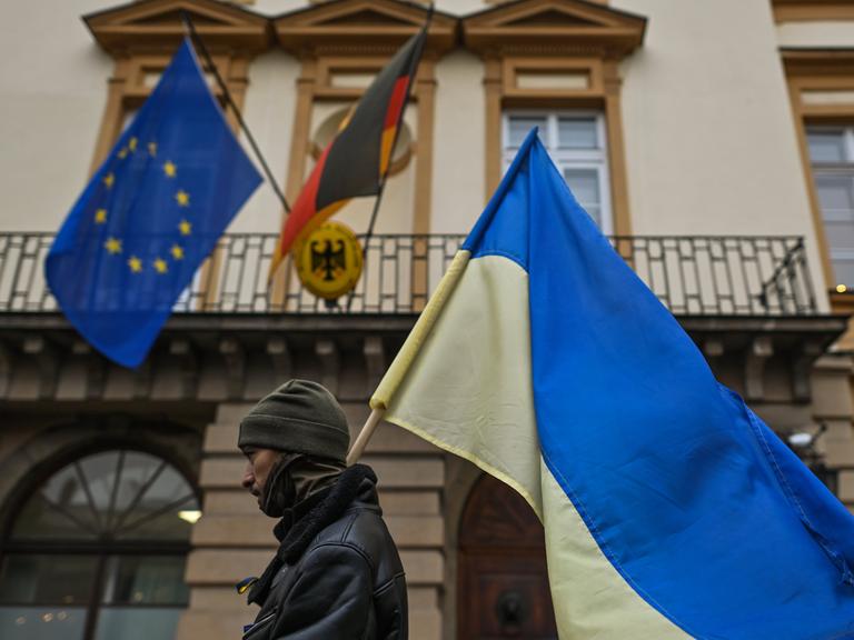 Ein Polin geht mit einer ukrainischen Flagge am Generalkonsulat der Bundesrepublik Deutschland in Krakau vorbei, während des "Protestes zur Unterstützung der Ukraine".
