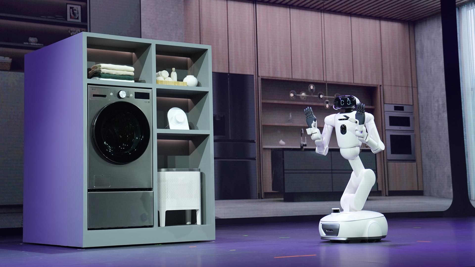 Das Foto zeigt den Blick auf eine Bühne. Dort sind ein Roboter und mehrere traditionelle Haushaltsgeräte wie eine Waschmaschine zu sehen.