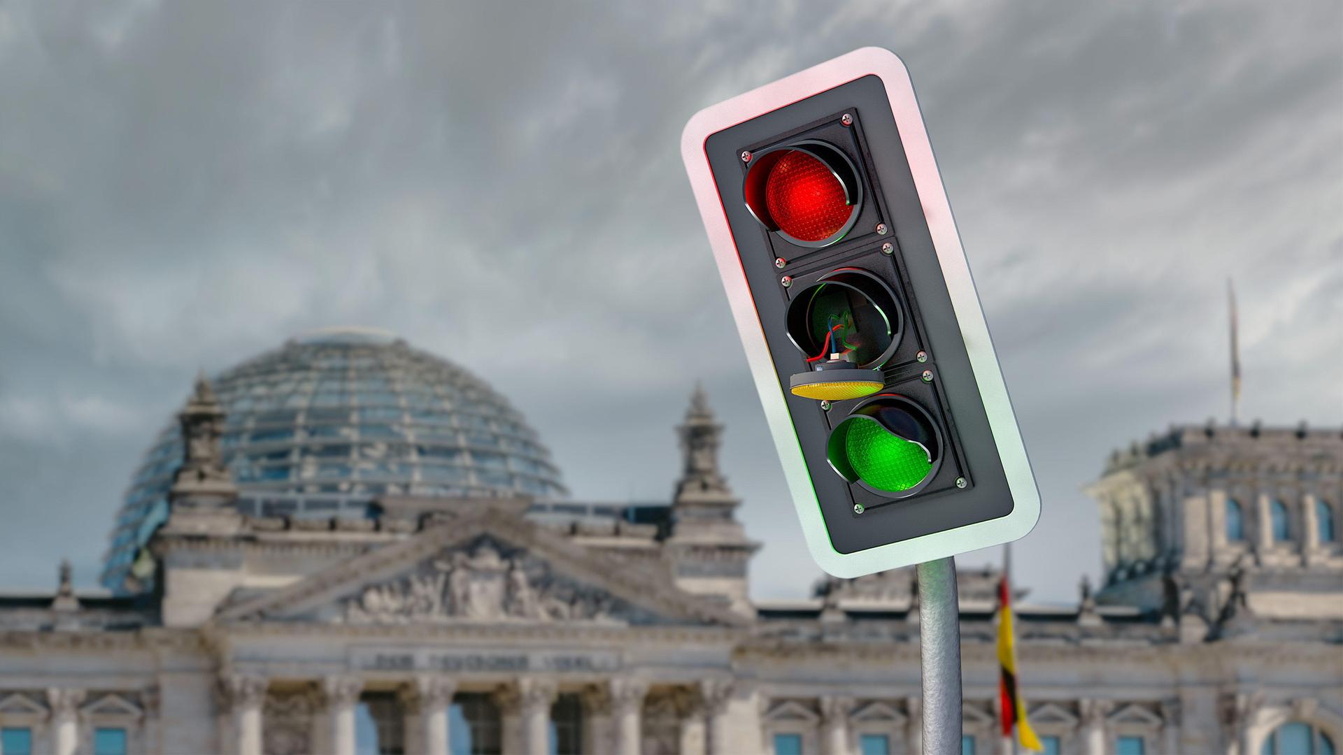 Eine Fotomontage zeigt eine ramponierte Ampel mit einem herausgesprungenen Gelb-Licht vor dem Hintergrund des Reichstagsgebäudes.