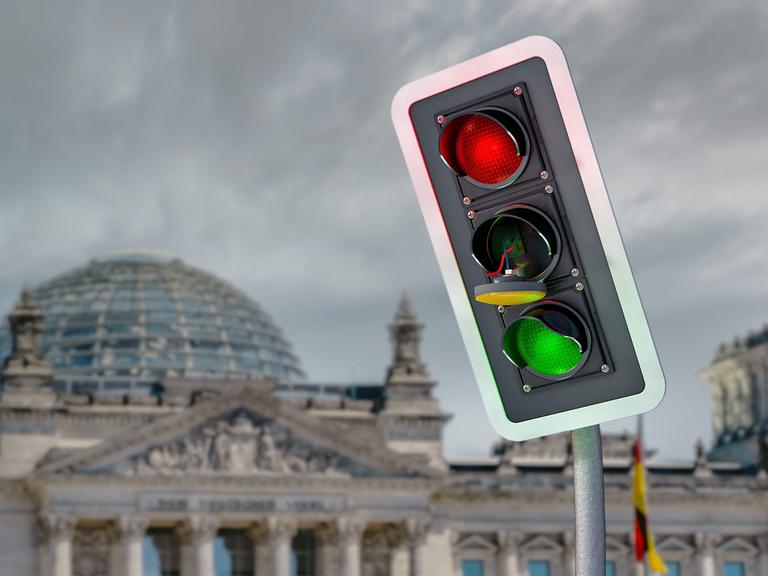 Eine Fotomontage zeigt eine ramponierte Ampel mit einem herausgesprungenen Gelb-Licht vor dem Hintergrund des Reichstagsgebäudes.