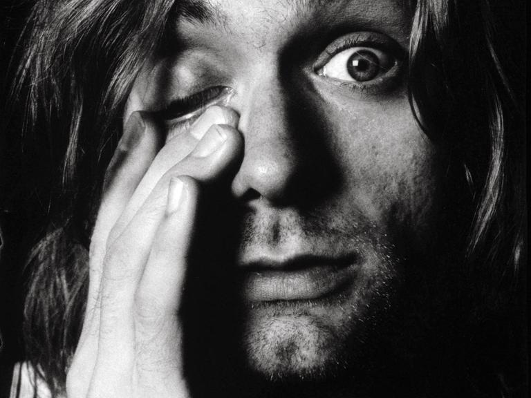 Kurt Cobain blickt in die Kamera, das rechte Auge ist geschlossen.