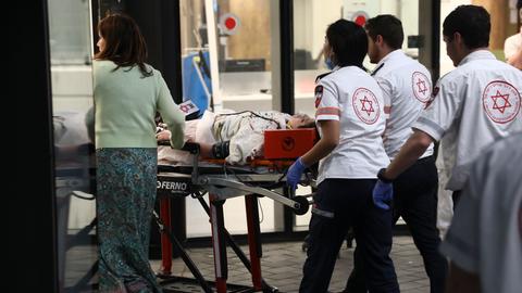 Eine verwundete Person wird von Sanitätern auf einer Trage ins Krankenhaus gebracht.