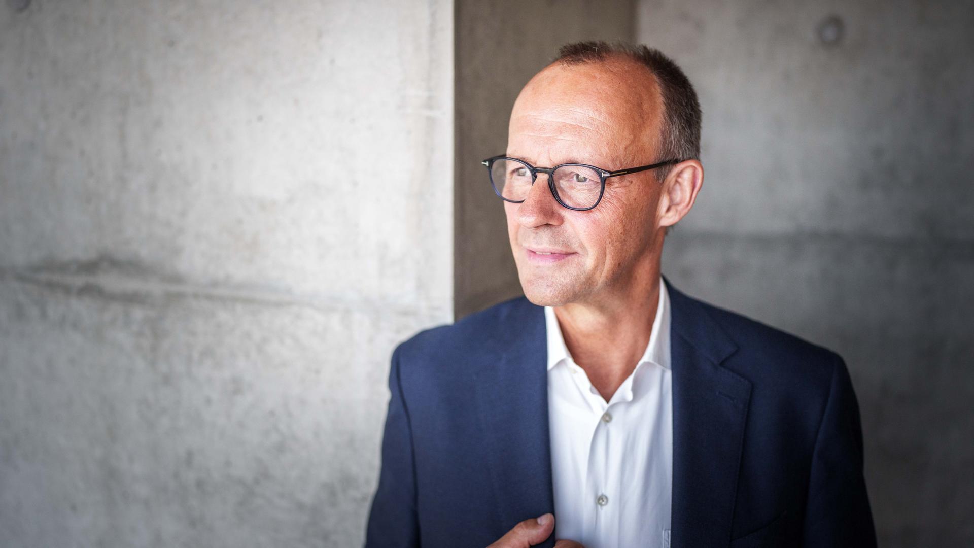 Friedrich Merz, CDU Bundesvorsitzender und CDUCSU Fraktionsvorsitzender im Bundestag. Er schaut links aus dem Bild heraus. Hinter ihm ene graue Betonwand.