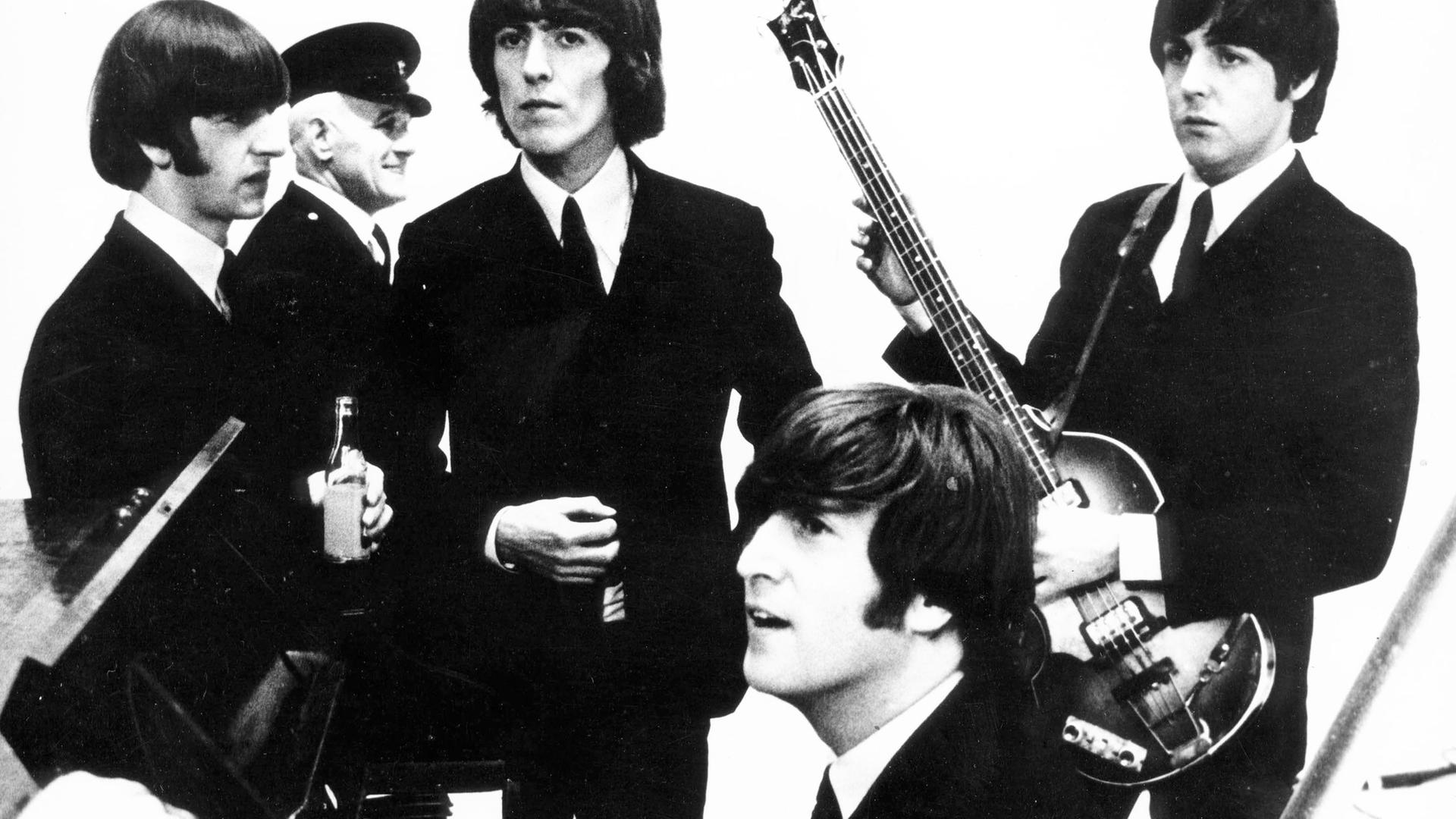 Die Beatles 1964 im Studio, John Lennon am Klavier. Dahinter: Ringo Starr, George Harrison und Paul McCartney.