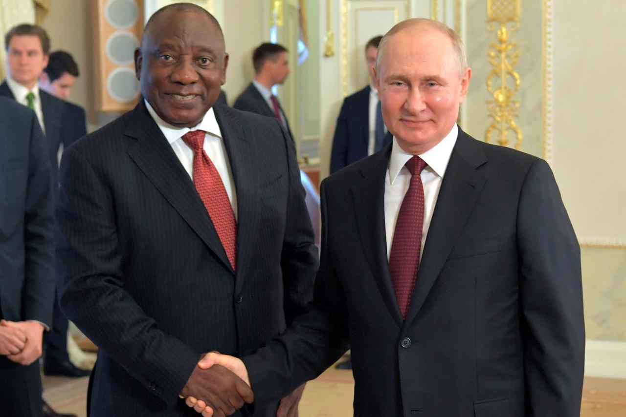Das Foto zeigt Wladimir Putin auf der rechten Seite Cyril Ramaphosa auf der Linken. Beide tragen dunkle Anzüge, lächeln in die Kamera und schütteln sich die Hände.