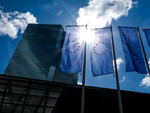 Das Gebäude der Europäische Zentralbank (EZB) und EU-Flaggen im Gegenlicht der Sonne