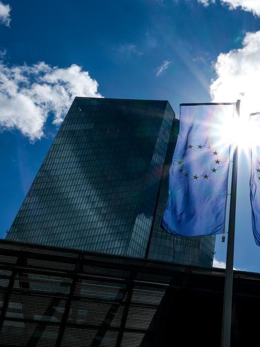 Das Gebäude der Europäische Zentralbank (EZB) und EU-Flaggen im Gegenlicht der Sonne