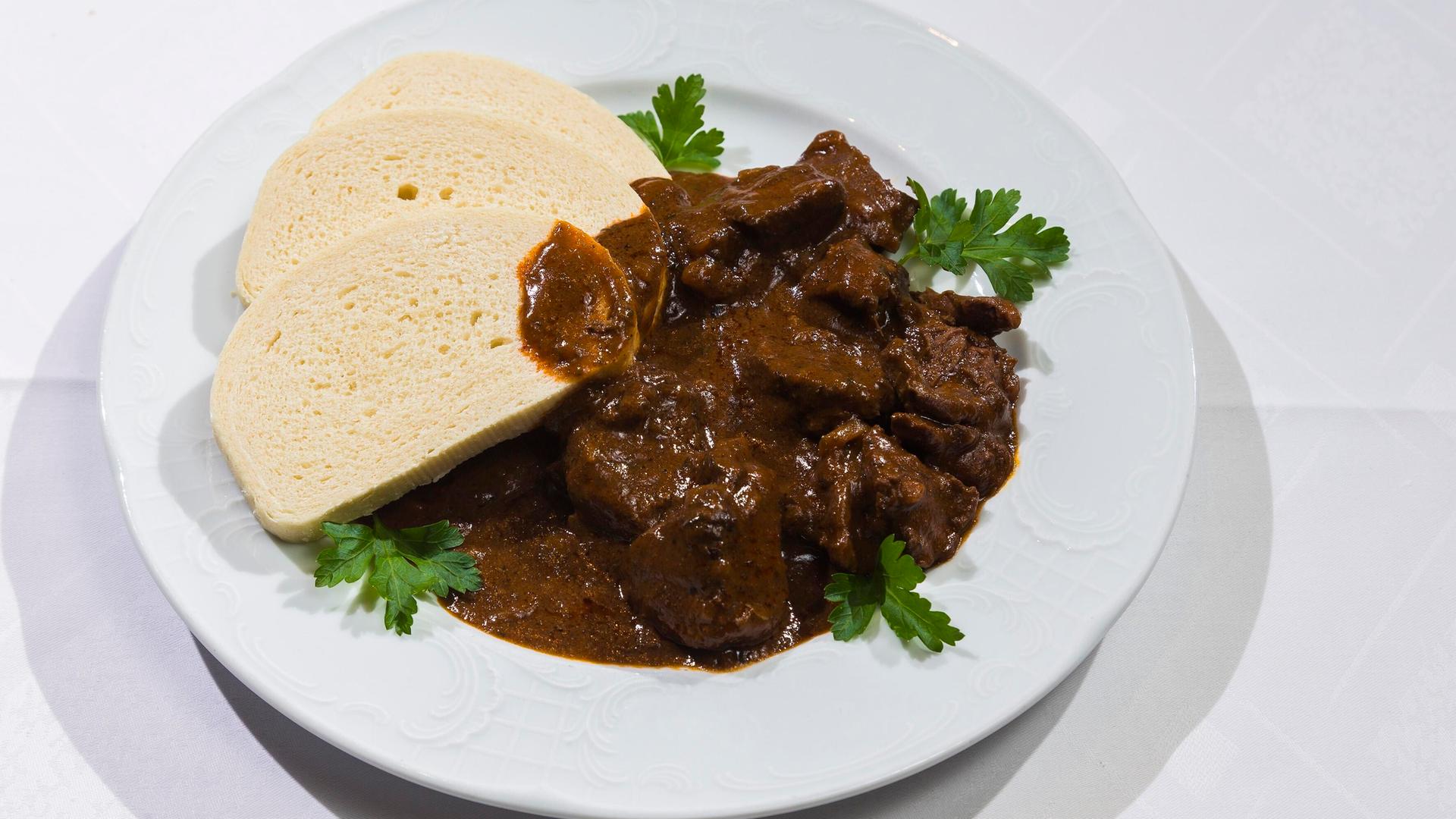 Auf einenm Teller ist ein Braten mit aufgeschnittenen Klossscheiben angerichtet. 