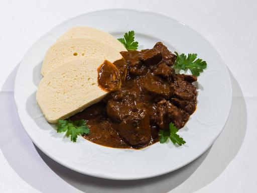 Auf einenm Teller ist ein Braten mit aufgeschnittenen Klossscheiben angerichtet. 