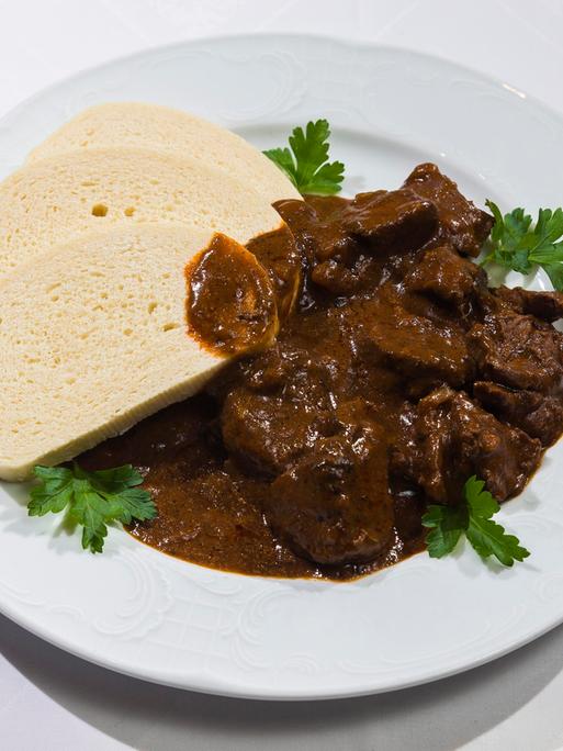 Auf einenm Teller ist ein Braten mit aufgeschnittenen Klossscheiben angerichtet. 