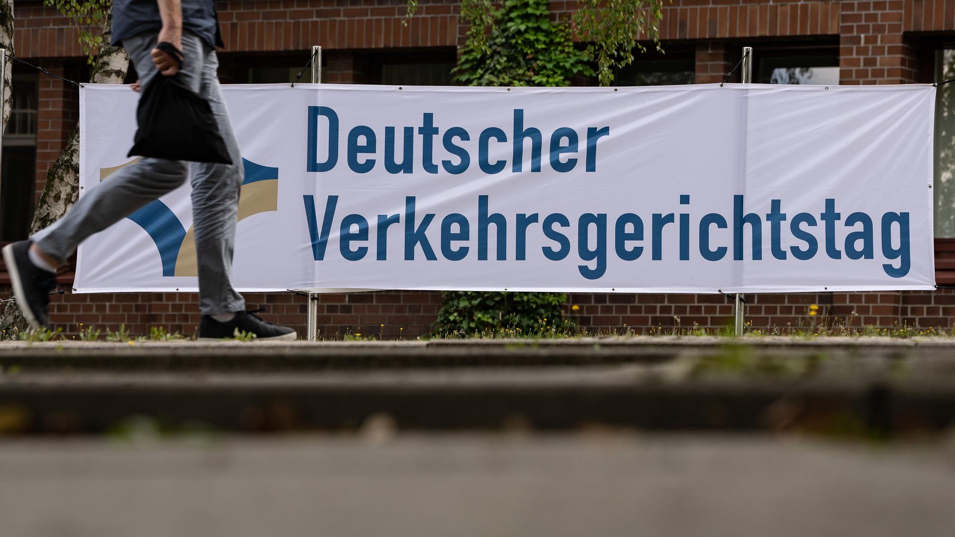 17.08.2022, Niedersachsen, Goslar: Ein Mann geht an einem Banner mit der Aufschrift «Deutscher Verkehrsgerichtstag» vorbei