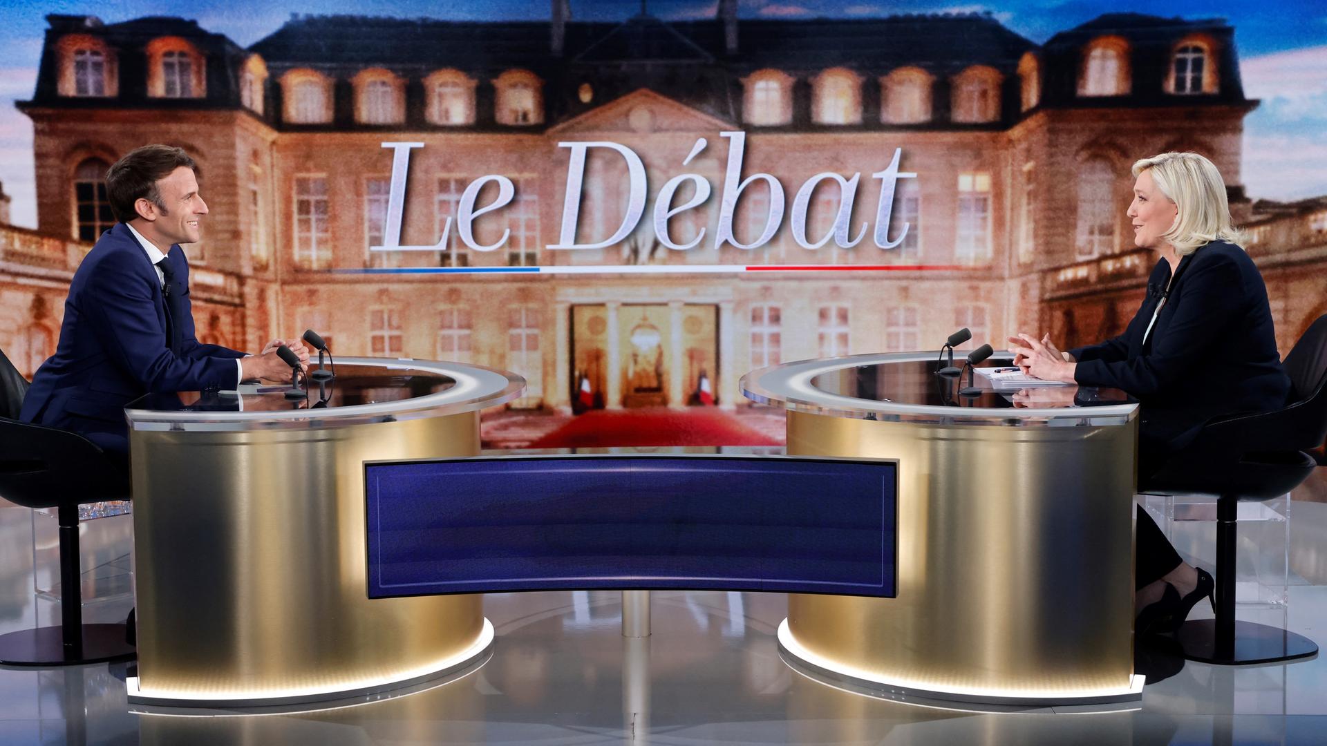 Amtsinhaber Macron und seine Herausforderin Le Pen sitzen jeweils an einem Tisch im Fernsehstudio. Amtsinhaber Macron und seine Herausforderin Le Pen sitzen jeweils an einem Tisch im Fernsehstudio.