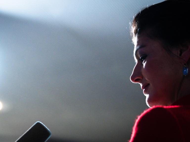 Sahra Wagenknecht ist im Profil vor einem dunklen Hintergrund zu sehen, ihr Gesicht ist beleuchtet