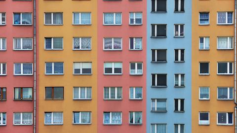 Mehrfarbige Fassade eines Wohnhauses mit zahlreichen Fenstern.