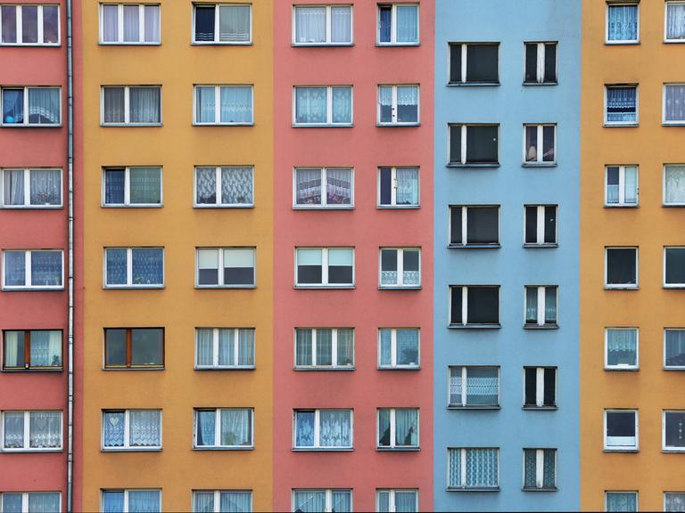 Mehrfarbige Fassade eines Wohnhauses mit zahlreichen Fenstern.