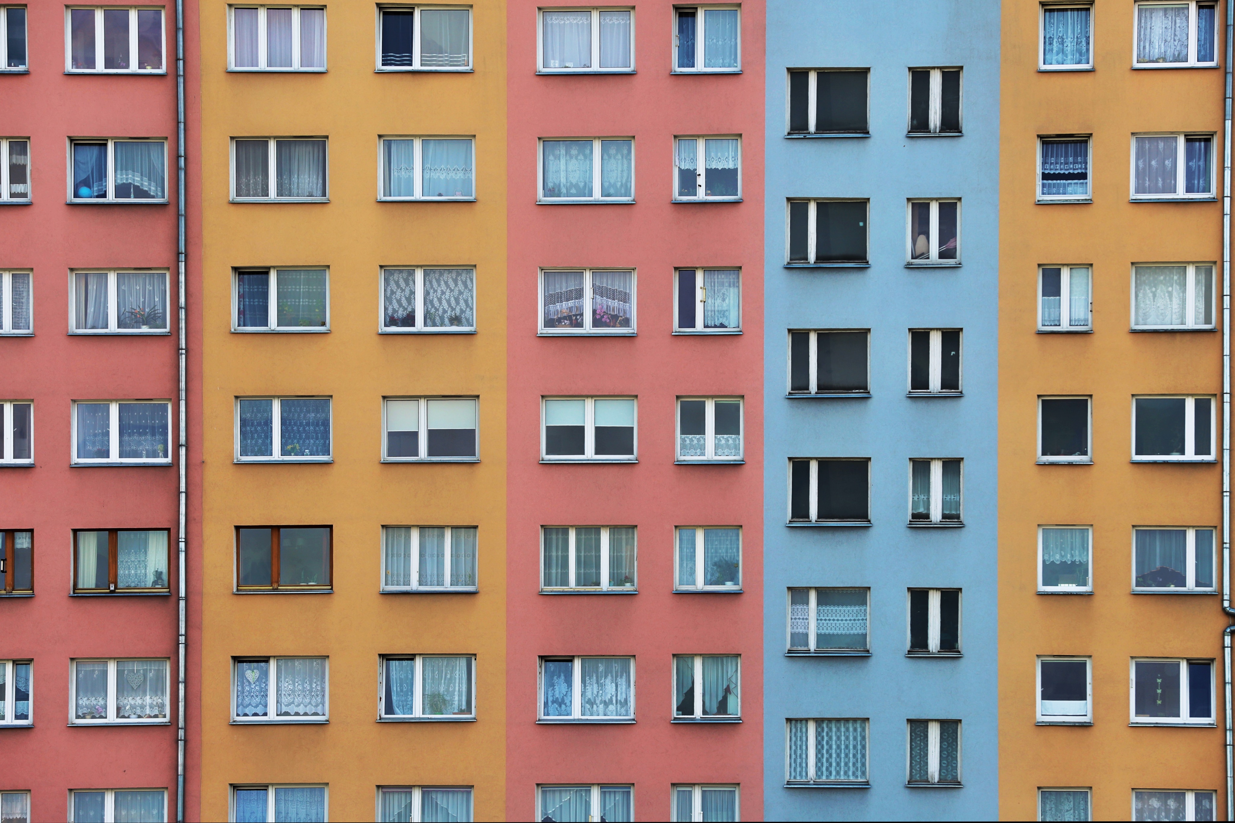 Mehrfarbige Fassade eines Wohnhauses mit zahlreichen Fenstern.