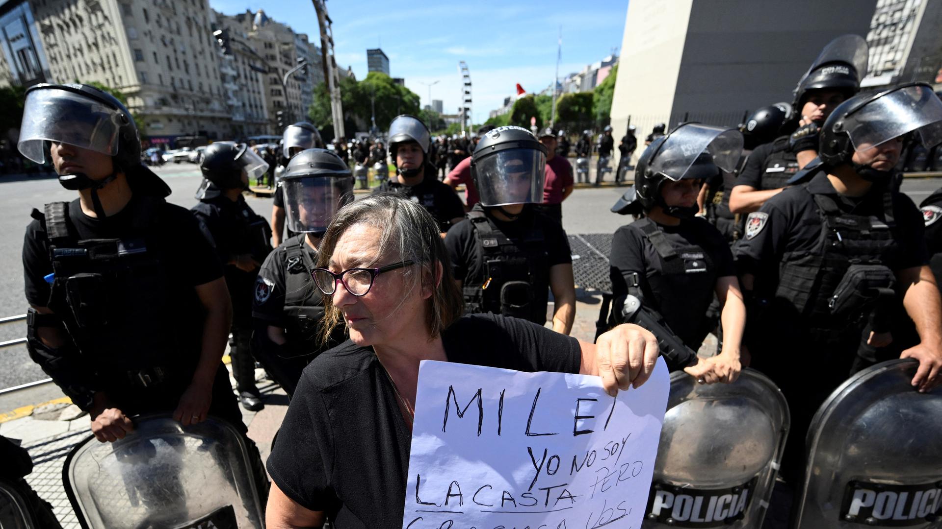 Demonstrationen in Argentinien gegen die Sparpolitik von Präsident Milei. Eine von Polizisten umringte Frau hält ein Protest-Plakat hoch. Demonstrationen in Argentinien gegen die Sparpolitik von Präsident Milei. Eine von Polizisten umringte Frau hält ein Protest-Plakat hoch.
