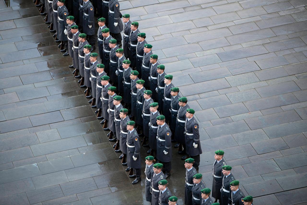 Drei Reihen von Soldaten eines Wachbataillons stehen auf grauem Pflaster.