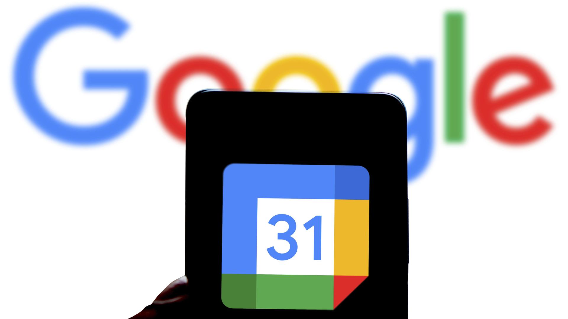 Das Google Kalender-Logo wird auf einem Smartphone angezeigt. Im Hintergrund ist der Schriftzug GOOGLE zu sehen. 