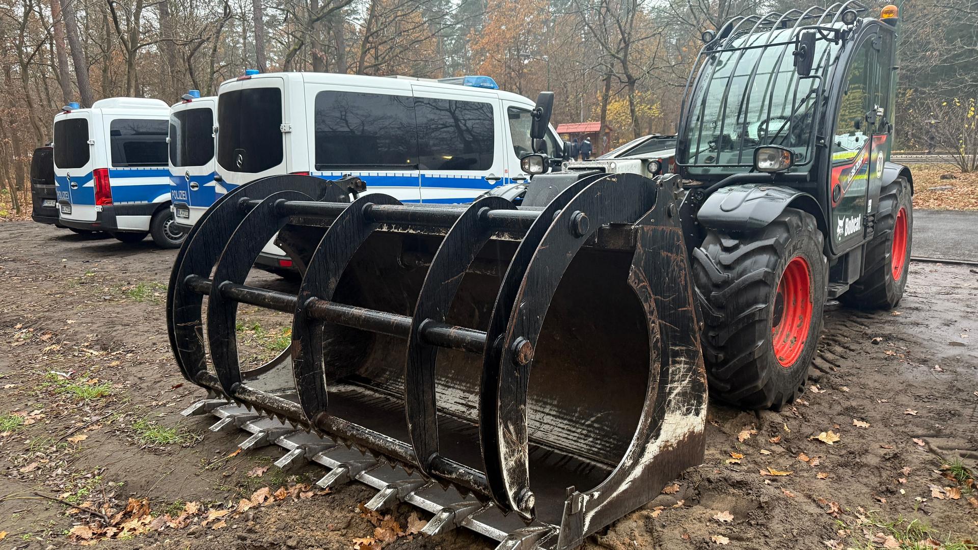 Einsatzfahrzeuge der Polizei und Räumgerät steht unweit des Tesla-Protestcamps im brandenburgischen Grünheide. 