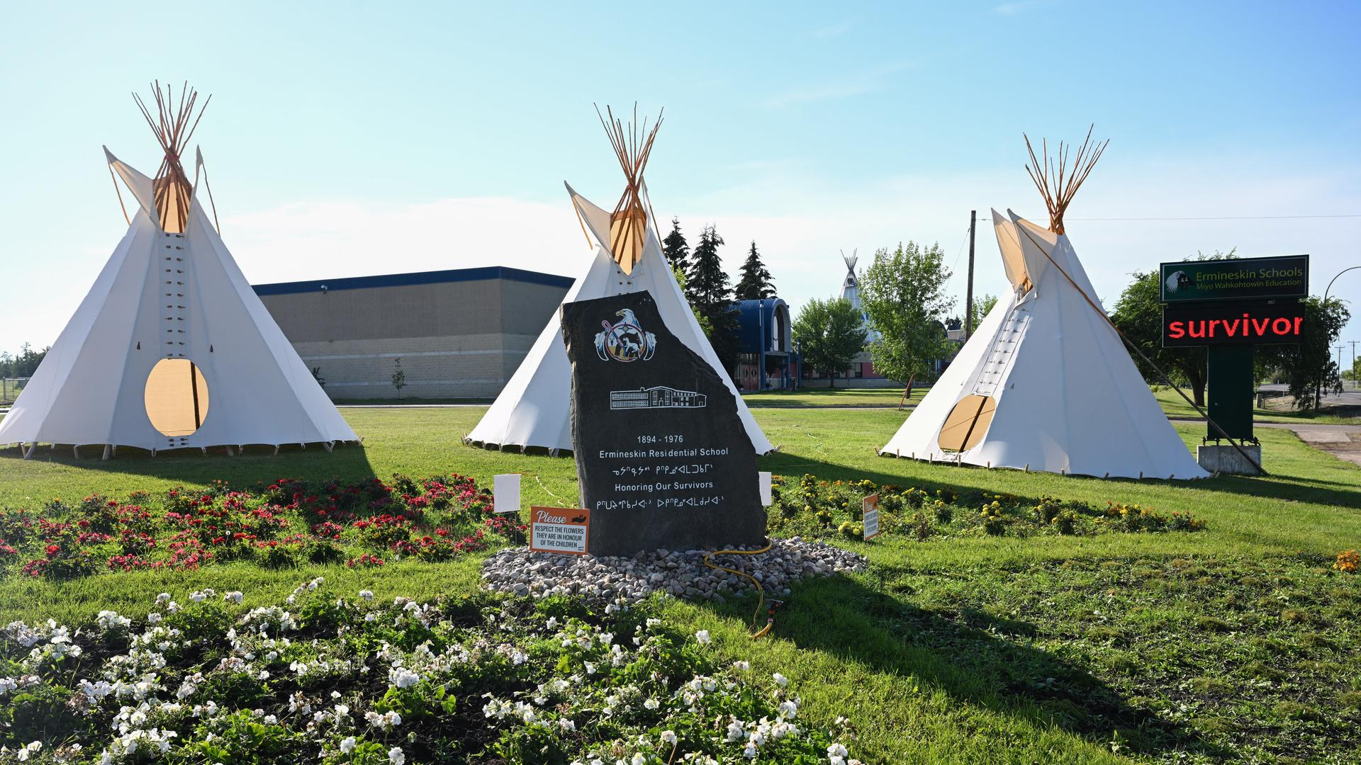 Ein steinernes Denkmal vor einigen Tipis im kanadischen Ort Maskwacis. Es erinnert an Opfer des Missbrauchs Schutzbefohlener in der von der katholischen Kirche betriebenen Ermineskin Indian Residential School.