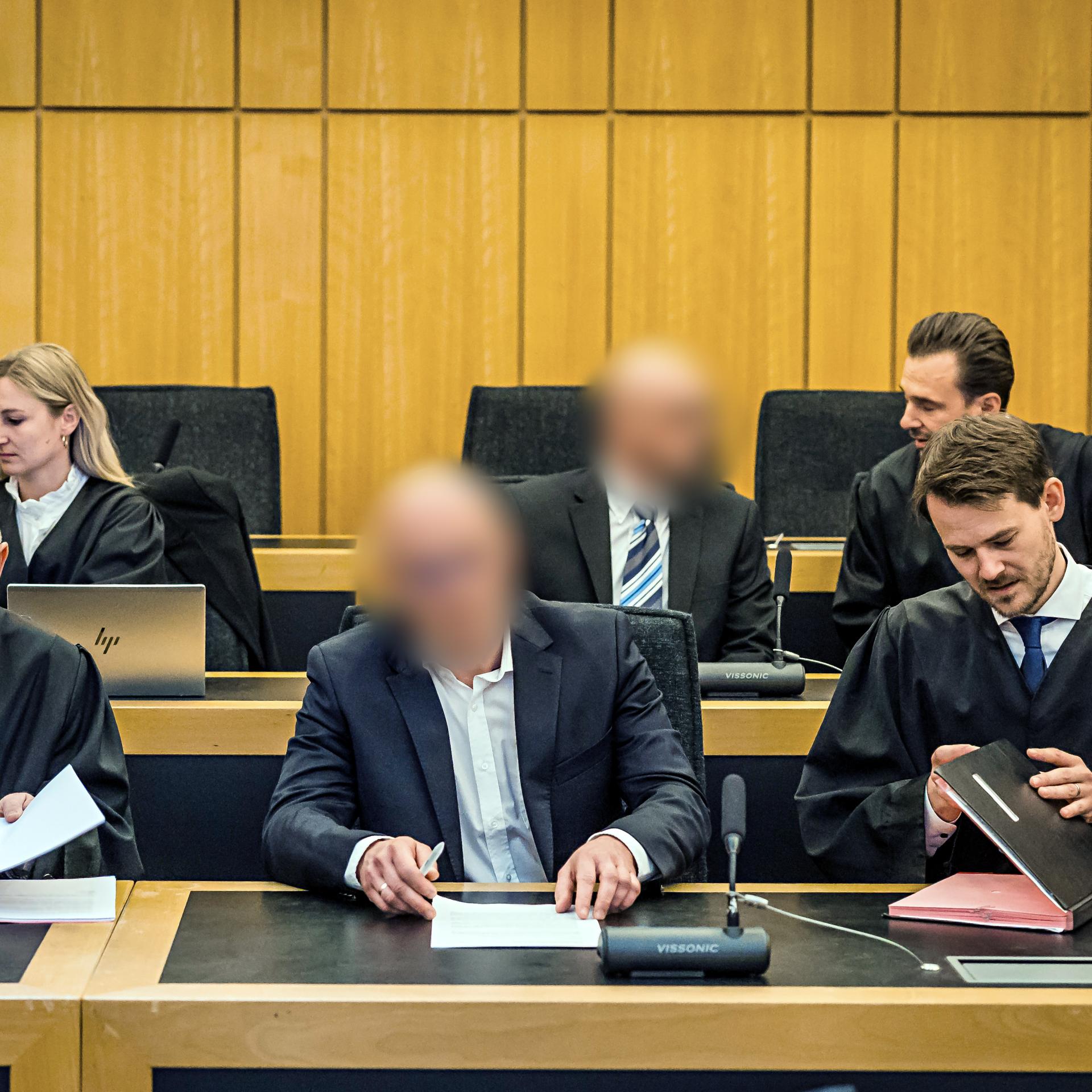 Die beiden Angeklagten sitzen zwischen ihren Anwälten im Gerichtssaal.