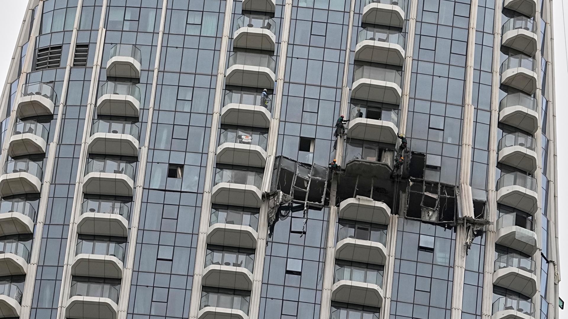 Arbeiter inspizieren die Schäden an der Fassade eines Hotels in Dubai.
