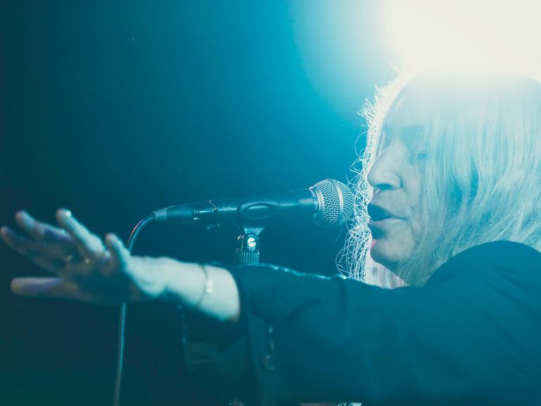 Patti Smith singt in sich versunken und in blaues Licht getaucht auf einer Bühne