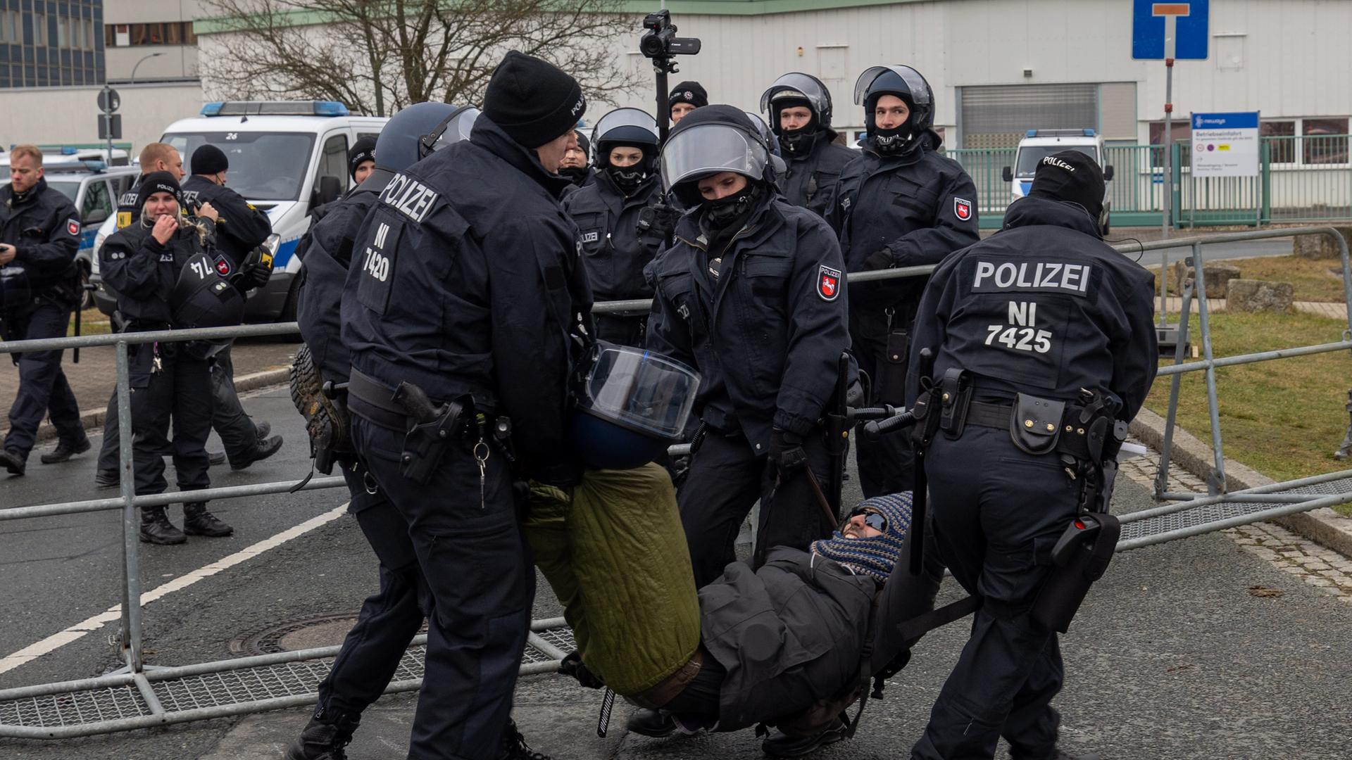 Mehrere Polizisten tragen einen vermummten Demonstranten weg.