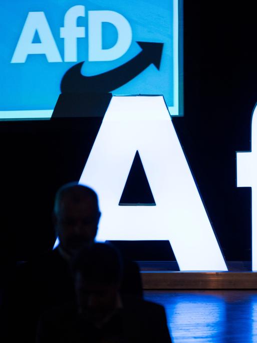 Ein großes weiß erleuchtetes AfD-Logo steht auf einer dunklen Bühne. Im Hintergrund ist das AfD-Logo ein weiteres mal, ebenfalls beleuchtet, zu sehen.