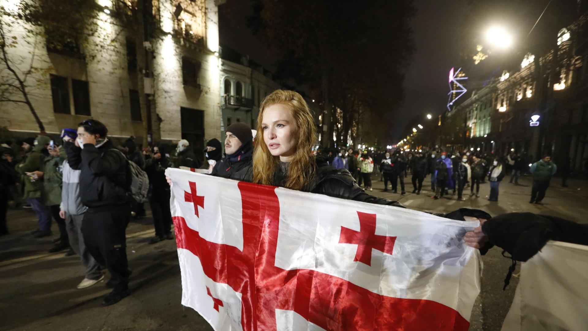 Eine Protestierende hält in der georgischen Hauptstadt Tiflis eine Flagge des Landes hoch.