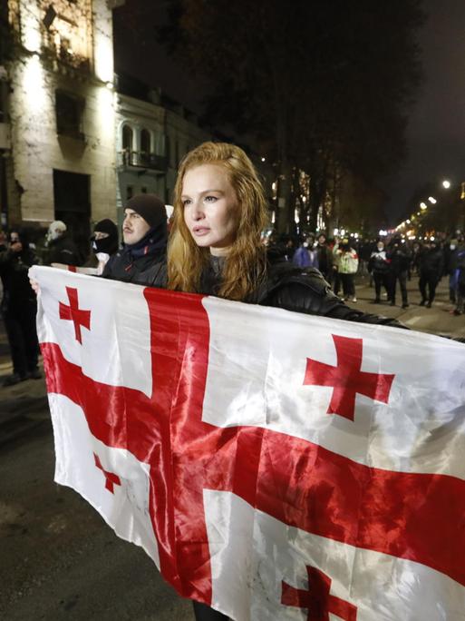 Eine Protestierende hält in der georgischen Hauptstadt Tiflis eine Flagge des Landes hoch.