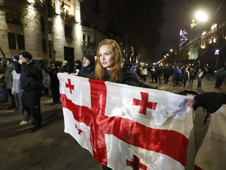 Eine Protestierende hält in der georgischen Hauptstadt Tiflis eine Flagge des Landes hoch.