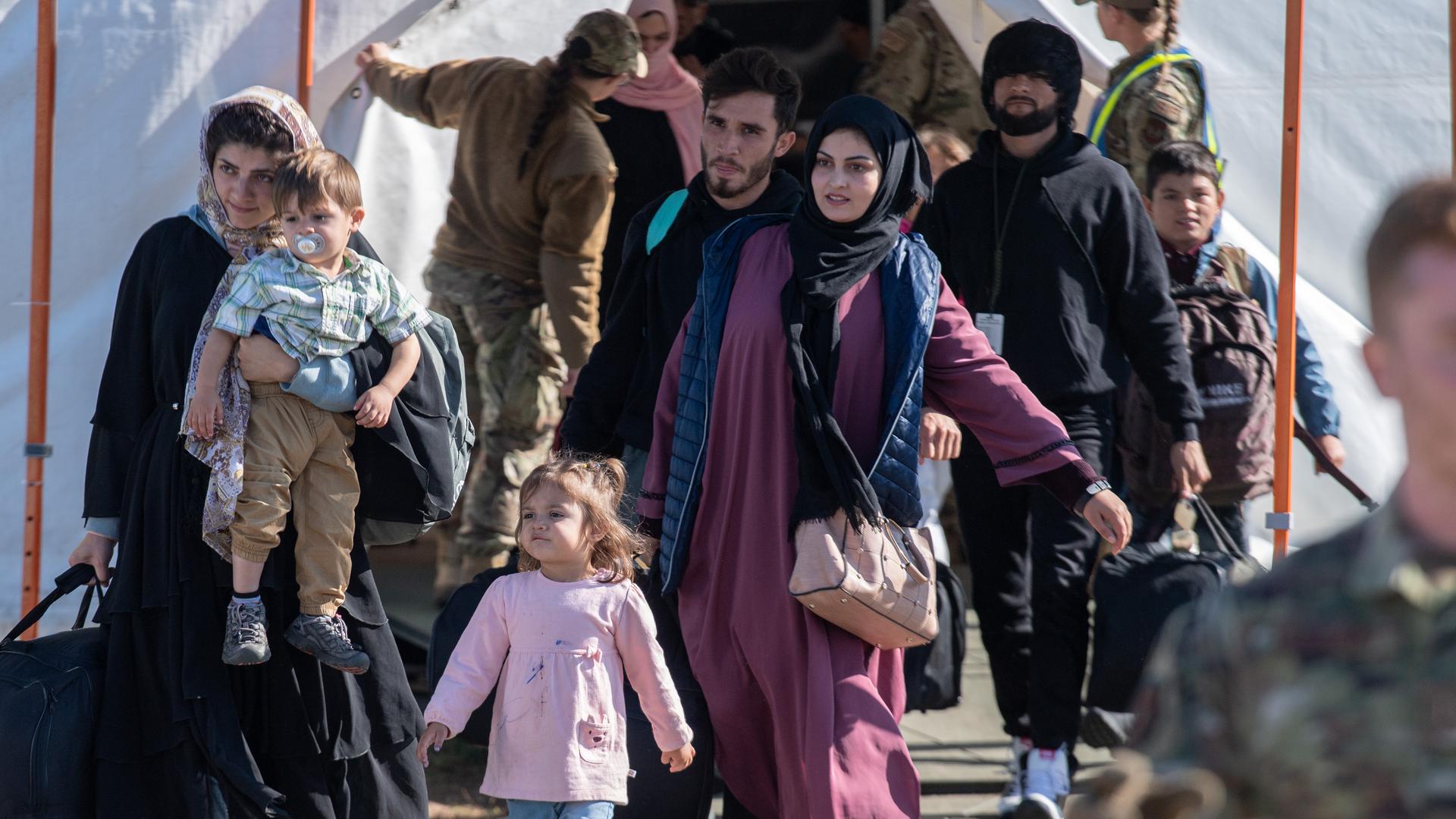 Kinder und Familien aus Afghanistan tragen vor ihrem Abflug in die USA ihr Gepäck zu einer Sammelstelle. 