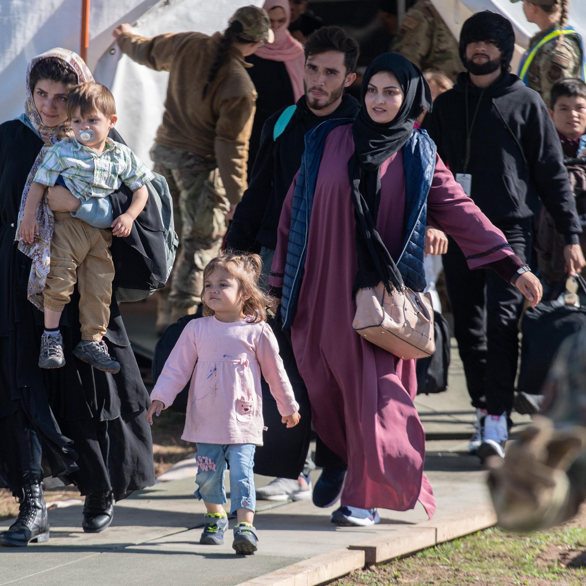 Kinder und Familien aus Afghanistan tragen vor ihrem Abflug in die USA ihr Gepäck zu einer Sammelstelle. 